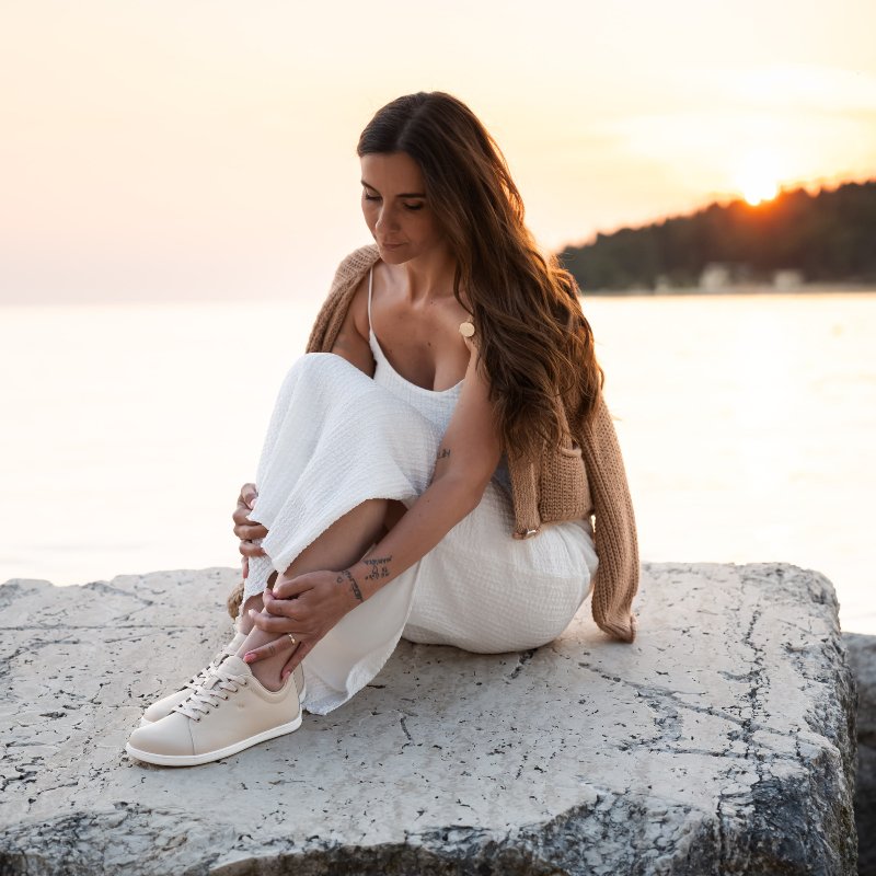Woman relaxing by the water in barefoot shoes