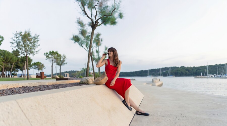 Person in barefoot ballet flats sitting on a seaside promenade on a summer evening