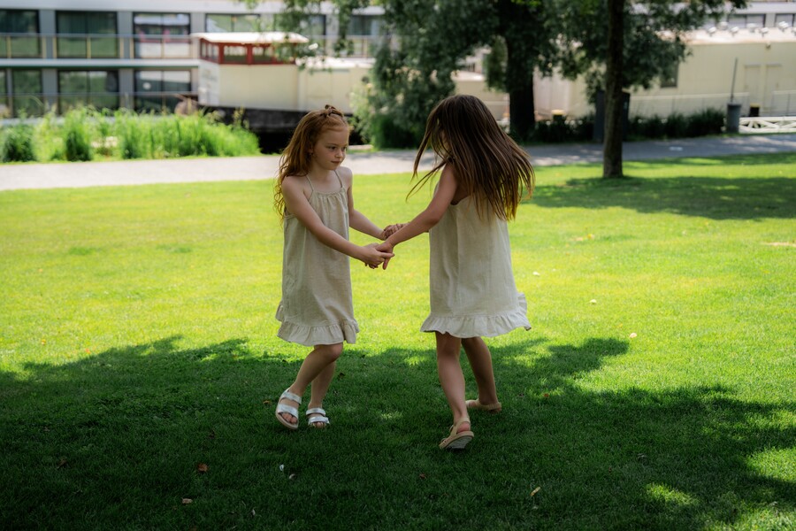 Dve deti v barefoot sandáloch sa hrajú na letnom trávniku