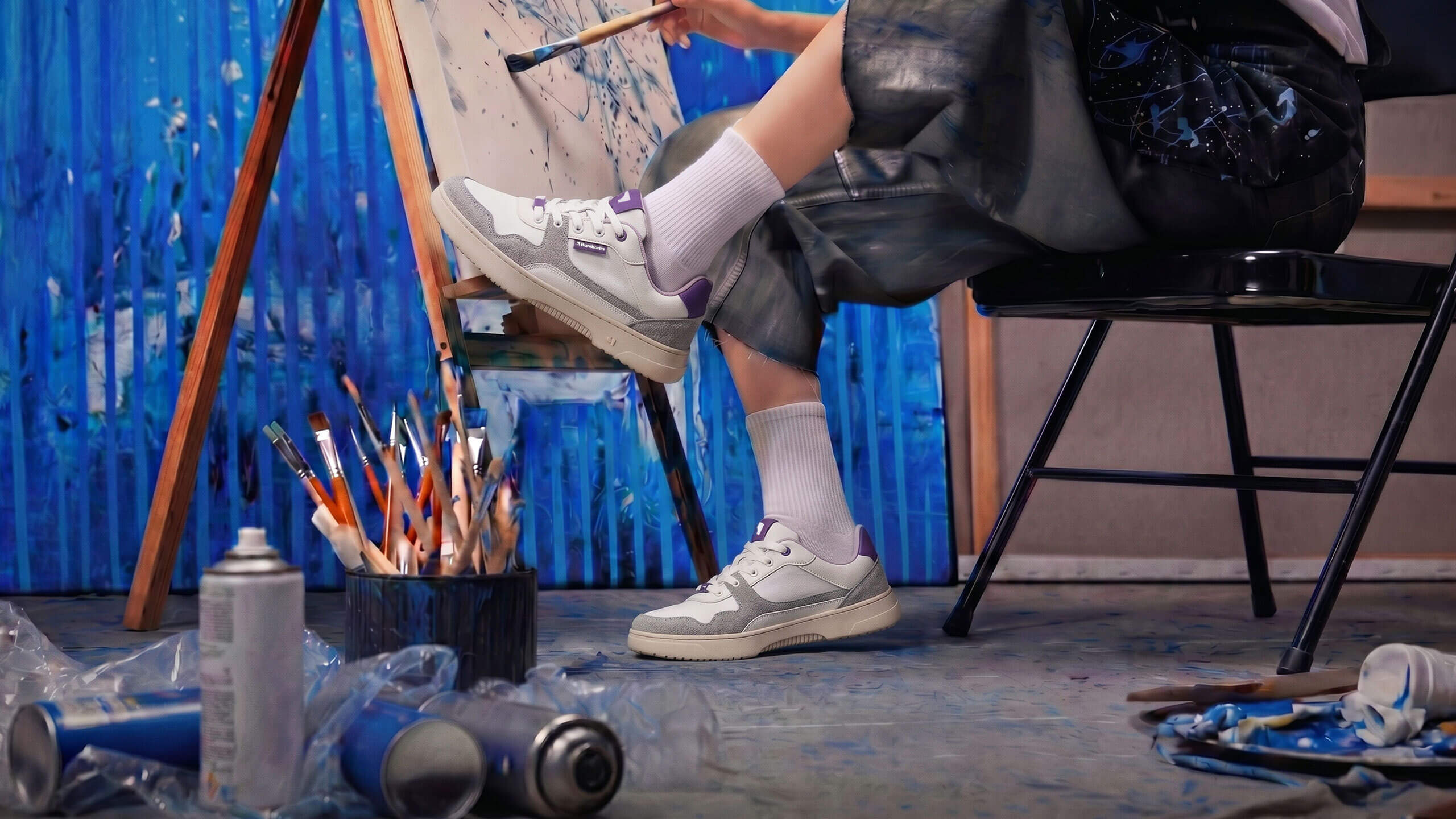 Person painting in a studio wearing white and grey Barebarics barefoot sneakers