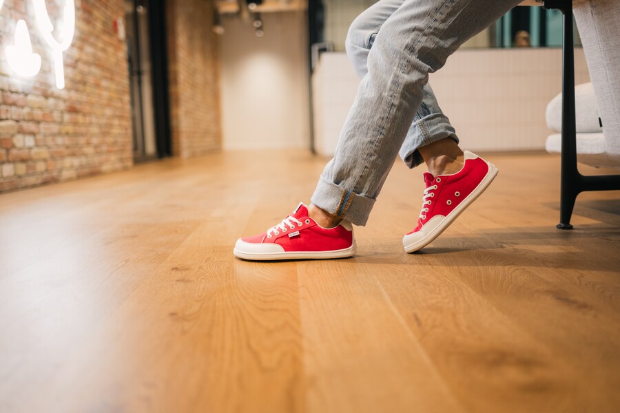 Close-up of red barefoot sneakers on a wooden floor indoors