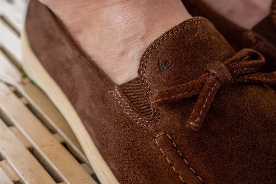 Close-up of a brown suede barefoot moccasin with lace detailing
