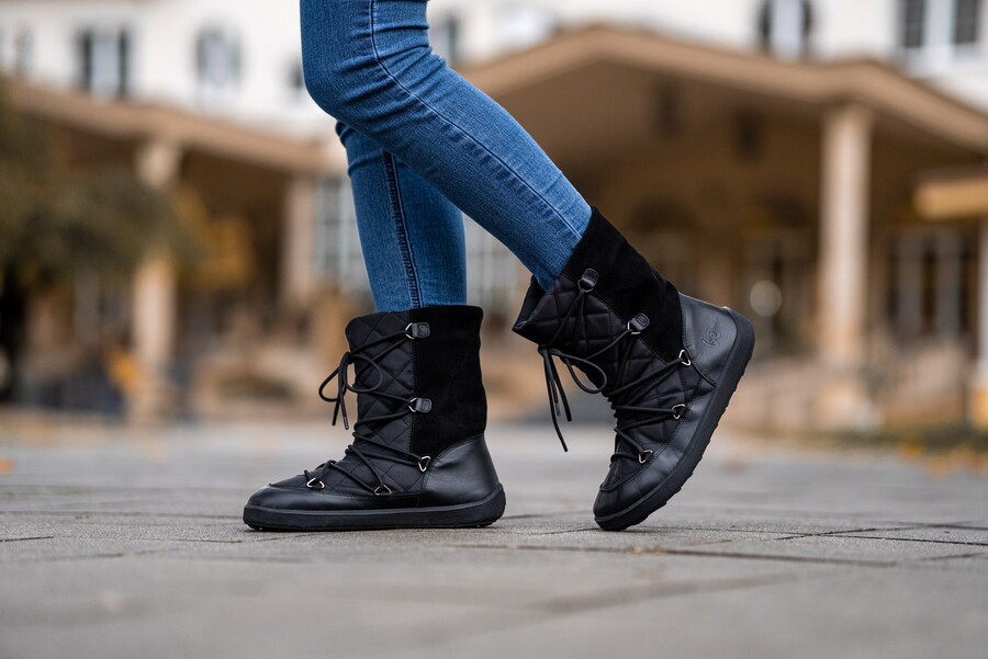 Person in black barefoot snow boots walking on a wintry pavement Person in black barefoot snow boots walking on a wintry pavement