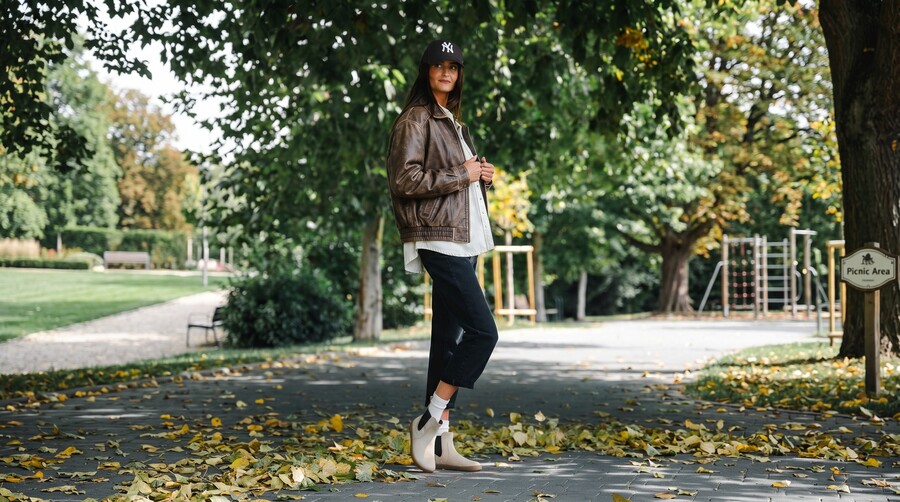 Person in light autumn barefoot shoes standing in a park among fallen leaves Person in light autumn barefoot shoes standing in a park among fallen leaves