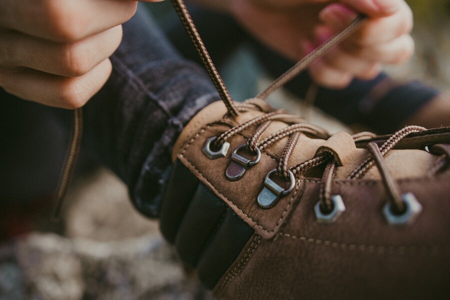 Close-up of hands tying laces on brown autumn barefoot shoes Close-up of hands tying laces on brown autumn barefoot shoes
