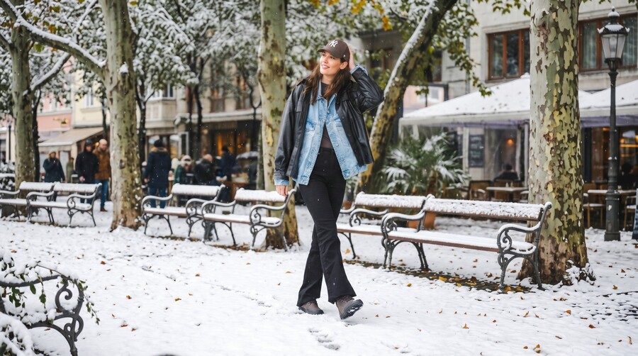 Person in winter barefoot boots walking across a snowy square in a city Person in winter barefoot boots walking across a snowy square in a city
