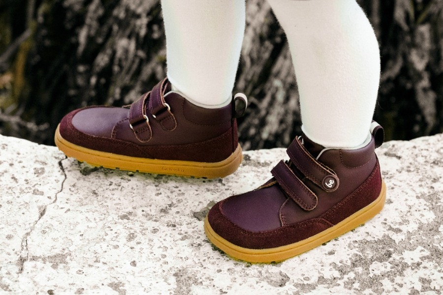 Gros plan de pieds d'enfant en chaussures barefoot toute l'année en cuir bordeaux à scratch Gros plan de pieds d'enfant en chaussures barefoot toute l'année en cuir bordeaux à scratch