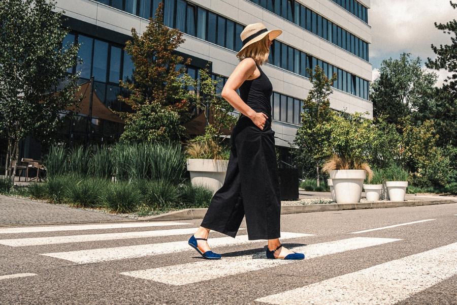 Kobieta w niebieskim damskim obuwiu barefoot przechodzi przez przejście w letnim mieście Kobieta w niebieskim damskim obuwiu barefoot przechodzi przez przejście w letnim mieście