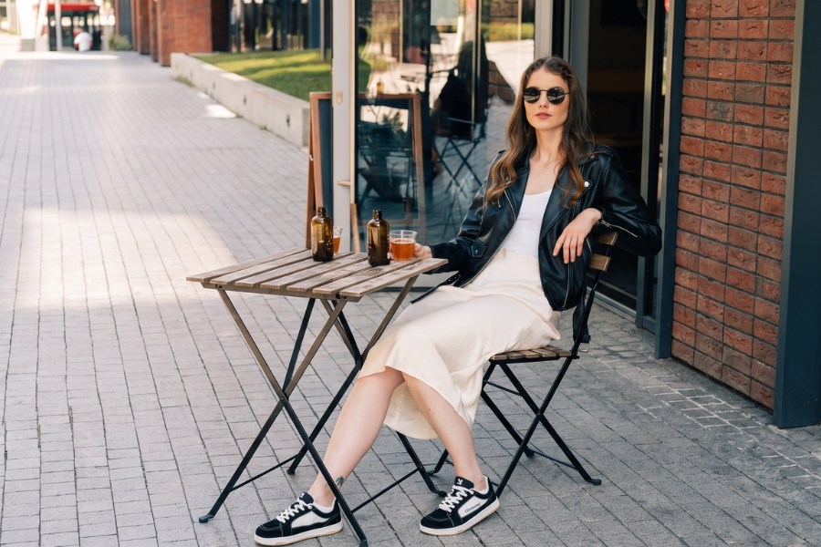 Woman in black and white women's Barebarics sneakers sitting at a café table Woman in black and white women's Barebarics sneakers sitting at a café table
