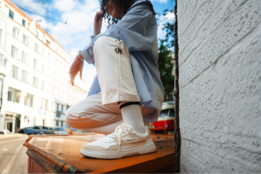 Woman in cream and white women's Barebarics sneakers in an urban setting Woman in cream and white women's Barebarics sneakers in an urban setting