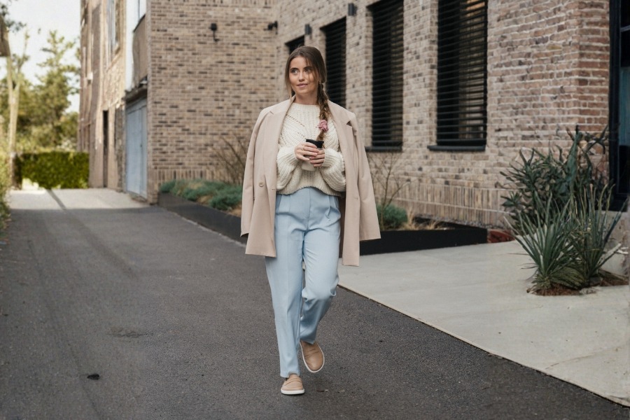 Woman in beige women's barefoot moccasins walking down a city alley Woman in beige women's barefoot moccasins walking down a city alley