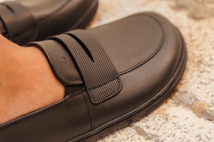 Close-up of a black leather women's barefoot moccasin with a strap across the instep Close-up of a black leather women's barefoot moccasin with a strap across the instep