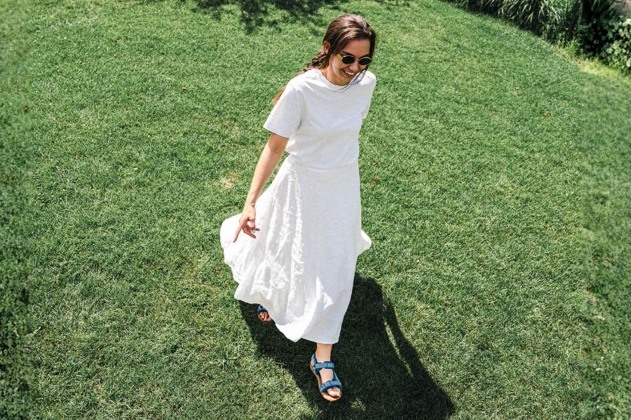 Woman in blue women's barefoot sandals walking across a summer lawn Woman in blue women's barefoot sandals walking across a summer lawn