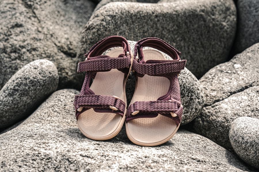 Women's barefoot sandals in burgundy placed on rocks Women's barefoot sandals in burgundy placed on rocks