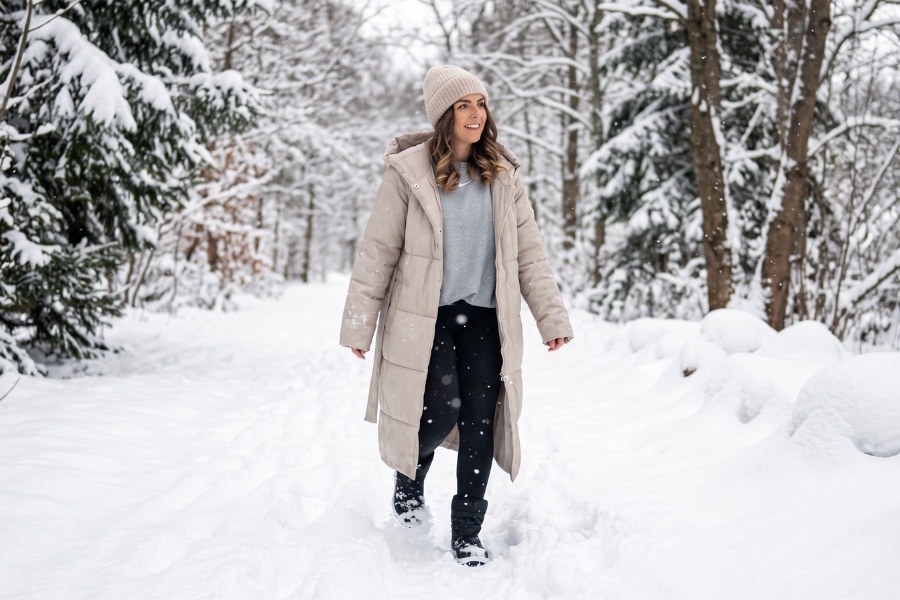 Woman in black and white women's barefoot snow boots walking along a snowy forest road