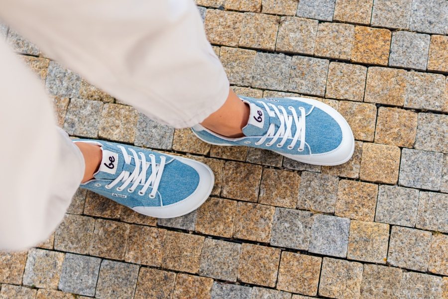 Top-down view of feet in blue women's everyday barefoot shoes on a pavement