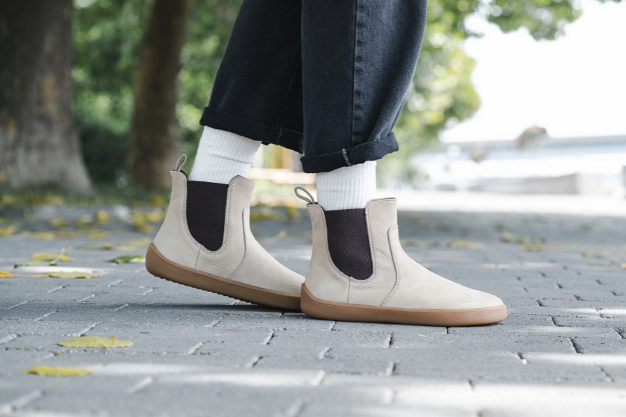 Close-up of feet in beige women's ankle barefoot boots on a pavement Close-up of feet in beige women's ankle barefoot boots on a pavement
