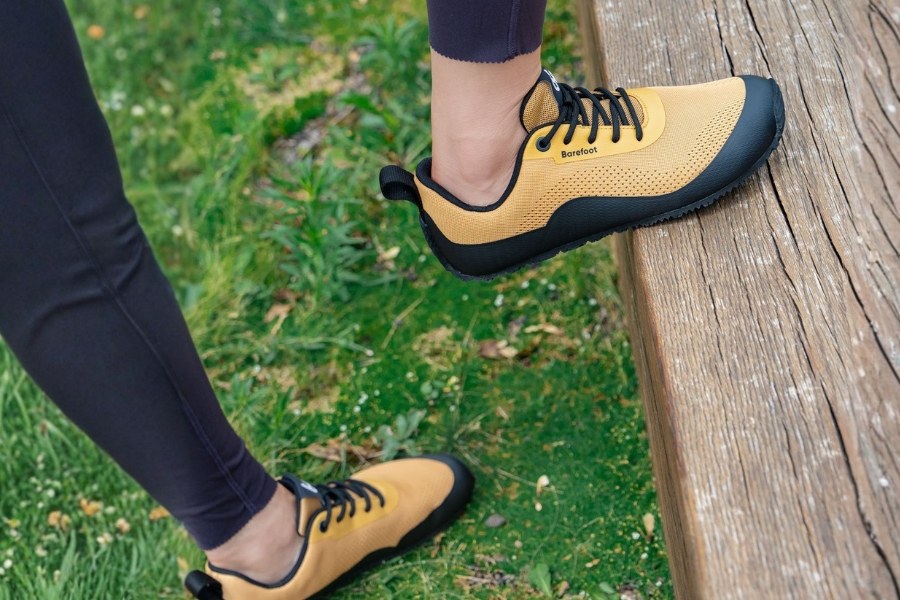 Close-up of feet in yellow women's autumn barefoot shoes in grass Close-up of feet in yellow women's autumn barefoot shoes in grass