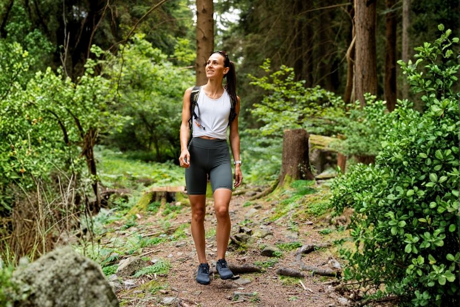 Kobieta w granatowych damskich outdoorowych butach barefoot idzie leśną ścieżką