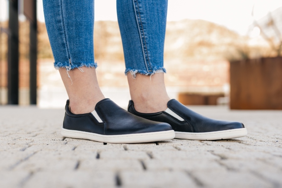 Close-up of feet in black women's slip-on barefoot shoes on cobblestones Close-up of feet in black women's slip-on barefoot shoes on cobblestones