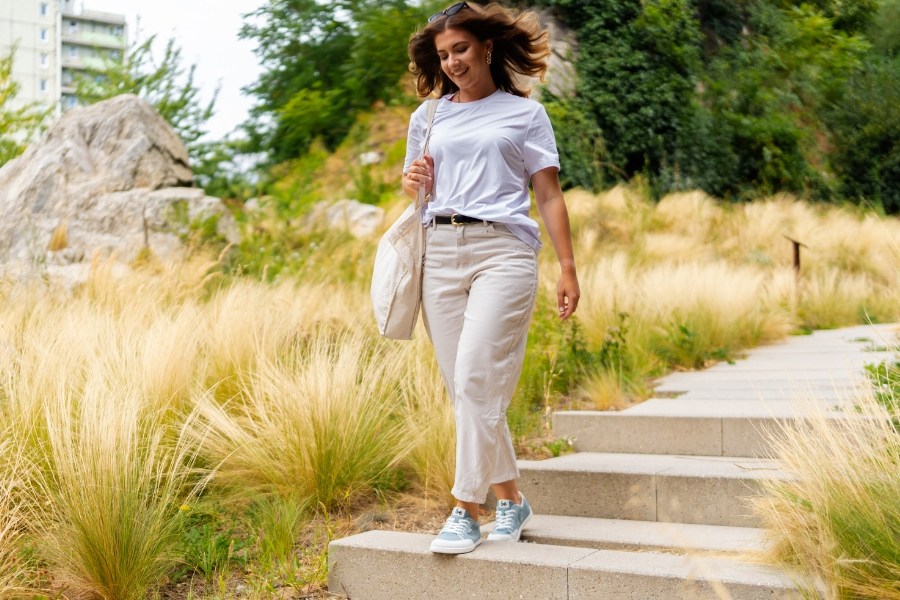 Woman in light blue women's vegan barefoot shoes walking down steps in a park Woman in light blue women's vegan barefoot shoes walking down steps in a park