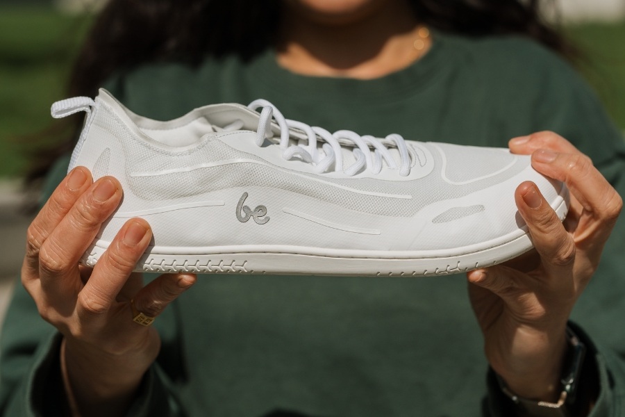 Woman holding a white women's vegan barefoot shoe made of breathable material Woman holding a white women's vegan barefoot shoe made of breathable material