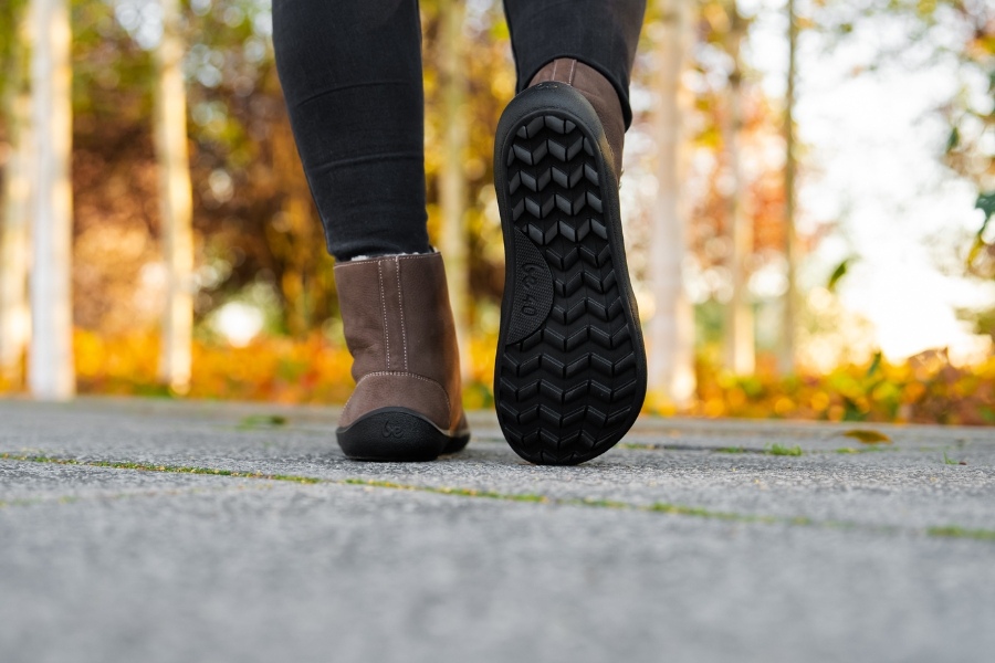 Rear view of feet in brown women's winter barefoot shoes with a treaded sole