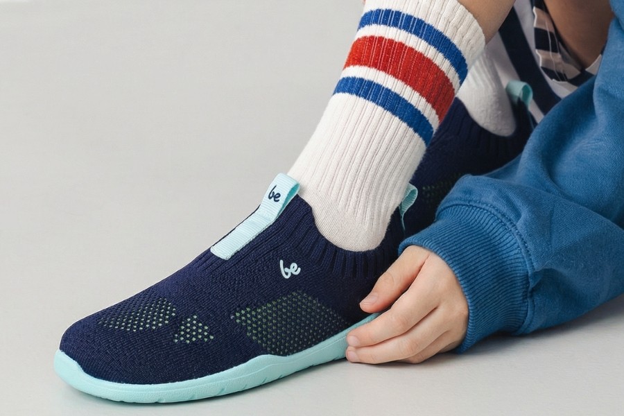 Close-up of navy knitted kids' barefoot slip-ons with a flexible turquoise sole. Close-up of navy knitted kids' barefoot slip-ons with a flexible turquoise sole.