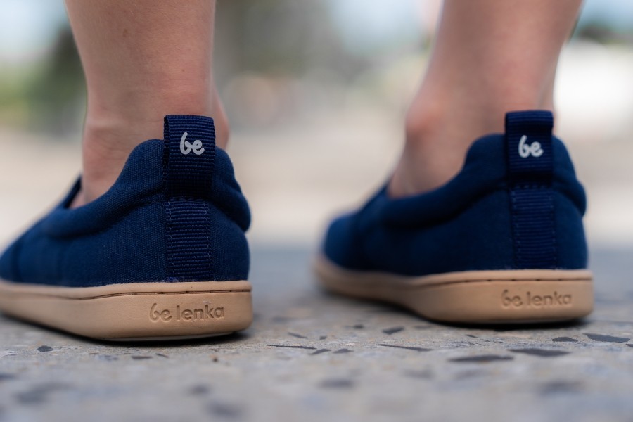 Rear close-up of navy kids' barefoot slip-ons with a gum sole and a heel pull tab. Rear close-up of navy kids' barefoot slip-ons with a gum sole and a heel pull tab.