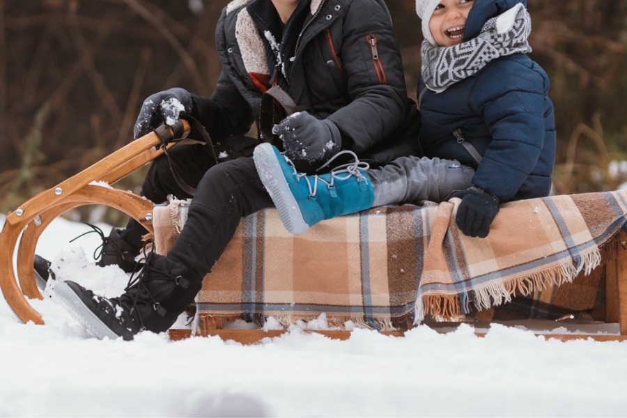 Close-up of a child's feet in navy kids' barefoot snow boots in a snowy forest Close-up of a child's feet in navy kids' barefoot snow boots in a snowy forest