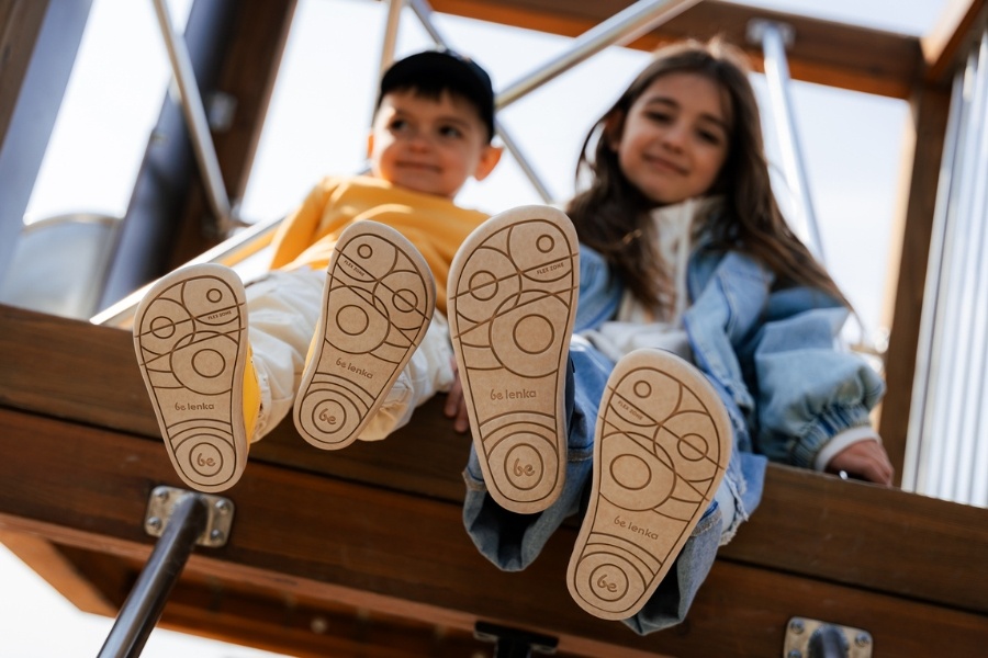 Close-up of the flexible soles of kids' barefoot sneakers on two children on a climbing frame