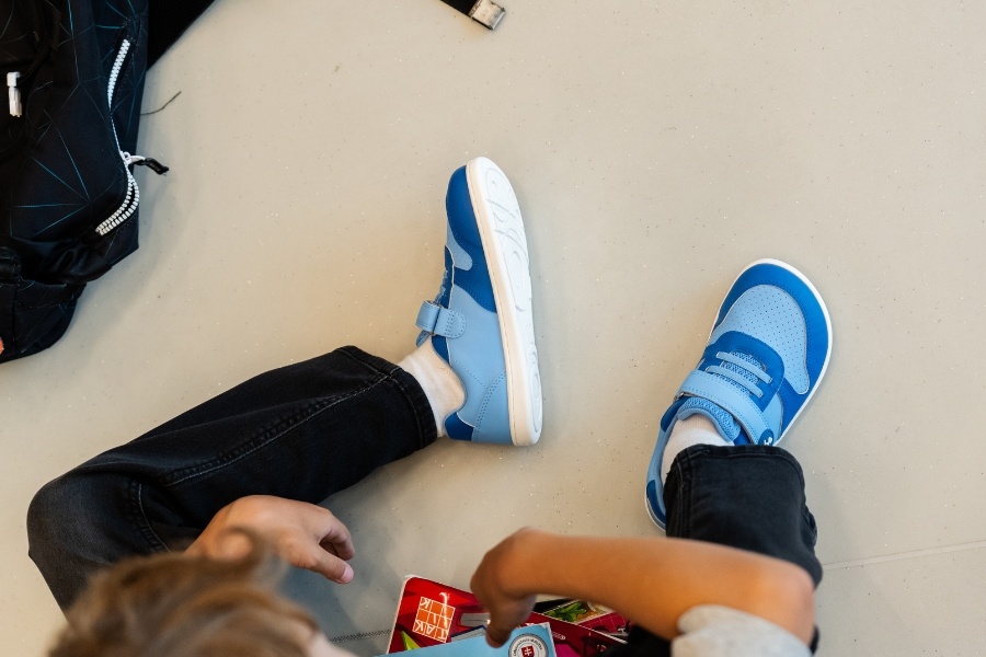 Vue de dessus de pieds d'enfant en chaussures barefoot bleues sur un sol clair Vue de dessus de pieds d'enfant en chaussures barefoot bleues sur un sol clair