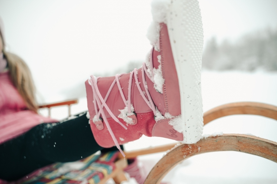 Close-up of a pink kids' winter barefoot shoe covered in snow while sledding Close-up of a pink kids' winter barefoot shoe covered in snow while sledding
