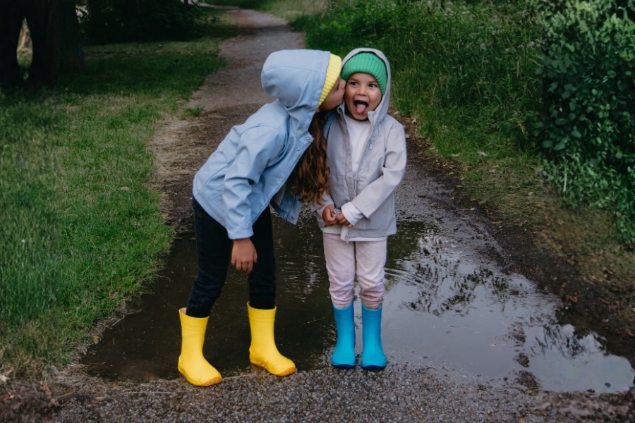 Two children standing by a puddle in yellow and blue waterproof kids' barefoot shoes for autumn. Two children standing by a puddle in yellow and blue waterproof kids' barefoot shoes for autumn.