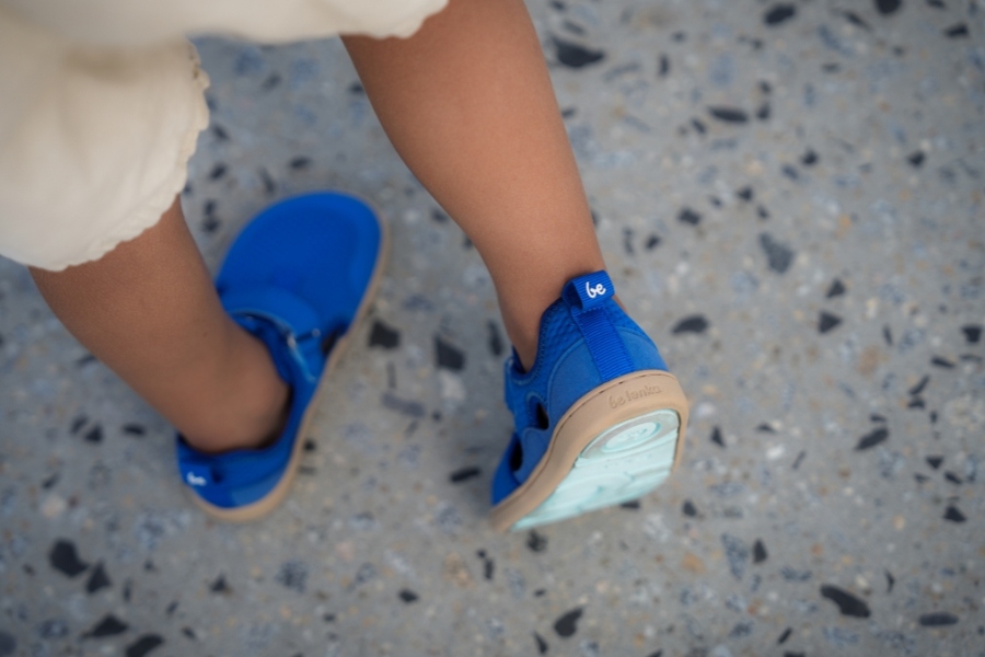 Top view of a child's feet in blue perforated kids' barefoot shoes for summer.