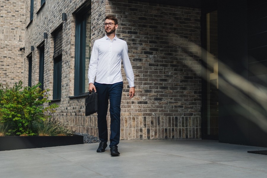 Homme en chaussures barefoot pour homme noires marchant avec une mallette près d'un bâtiment moderne Homme en chaussures barefoot pour homme noires marchant avec une mallette près d'un bâtiment moderne