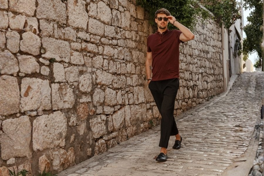 Man in black men's barefoot moccasins walking down a cobblestone alley in a seaside town Man in black men's barefoot moccasins walking down a cobblestone alley in a seaside town