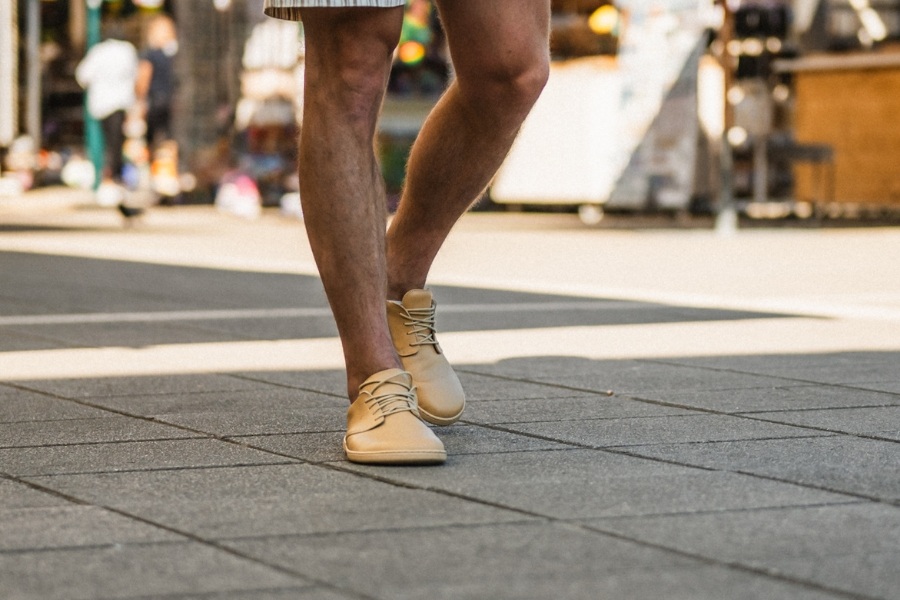 Homme en chaussures basses barefoot pour homme beige marchant sur un pavage urbain Homme en chaussures basses barefoot pour homme beige marchant sur un pavage urbain