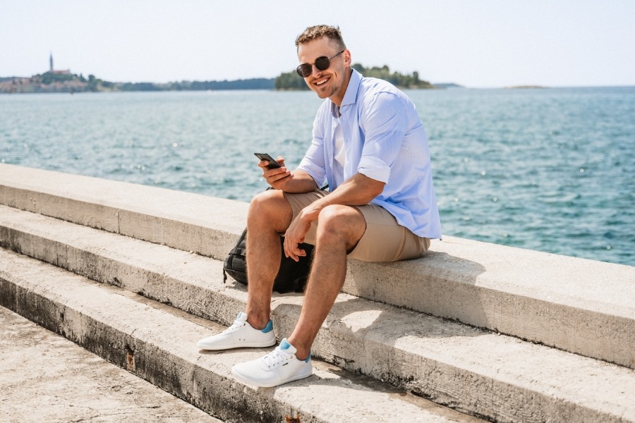 Homme en chaussures basses barefoot pour homme blanches assis sur des marches au bord de la mer Homme en chaussures basses barefoot pour homme blanches assis sur des marches au bord de la mer
