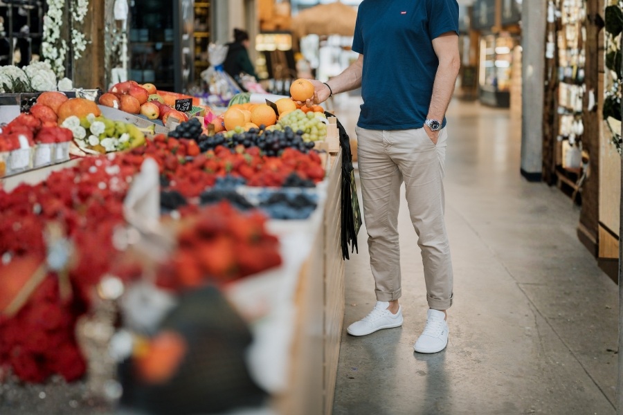 Homme en chaussures basses barefoot pour homme blanches choisissant des fruits au marché Homme en chaussures basses barefoot pour homme blanches choisissant des fruits au marché