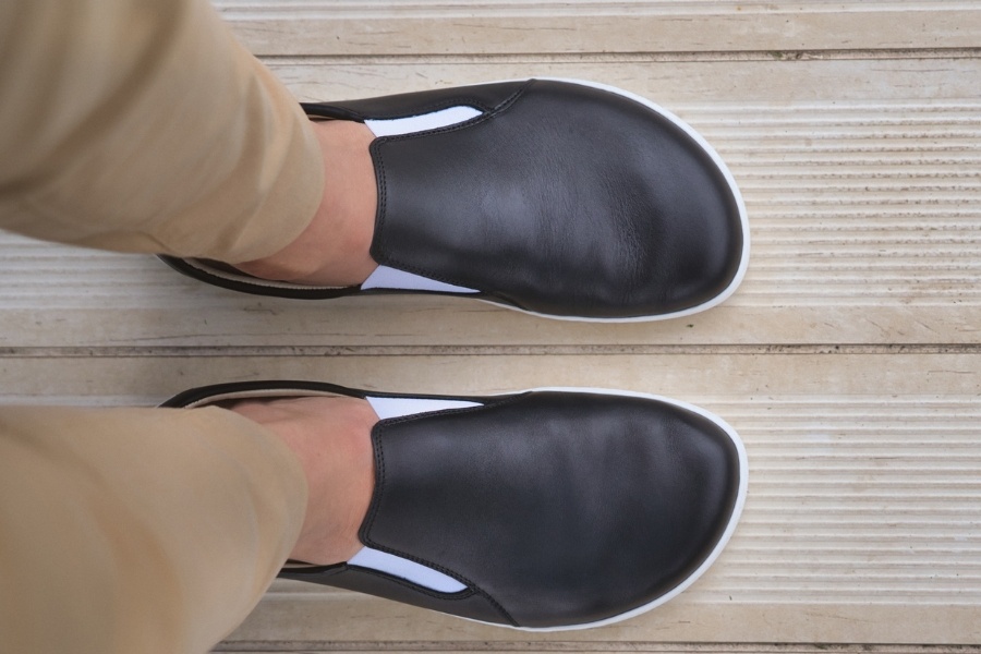 Top-down view of feet in black leather men's slip-on barefoot shoes Top-down view of feet in black leather men's slip-on barefoot shoes