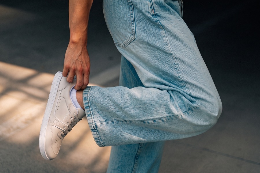 Close-up of a white men's barefoot sneaker held by a hand Close-up of a white men's barefoot sneaker held by a hand