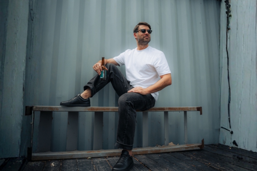 Man in black men's barefoot sneakers sitting on a metal bench Man in black men's barefoot sneakers sitting on a metal bench
