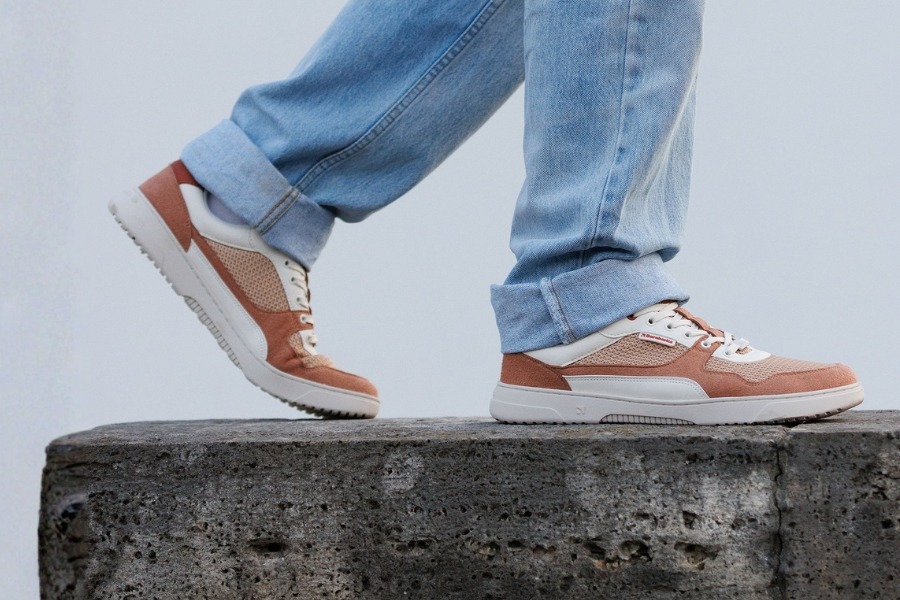 Close-up of feet in brown and cream men's barefoot sneakers on a concrete wall Close-up of feet in brown and cream men's barefoot sneakers on a concrete wall