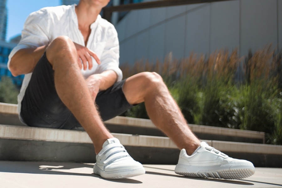 Man in white men's everyday barefoot shoes sitting on steps in the city
