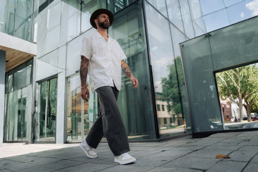 Man in beige and white men's everyday barefoot shoes walking on paving by a modern building