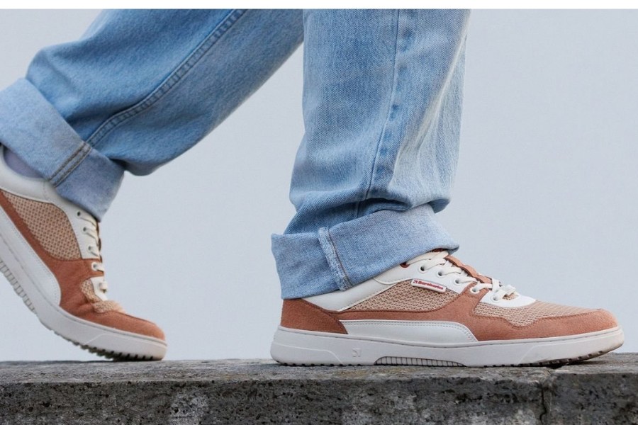Close-up of feet in brown and cream men's everyday barefoot shoes on a stone wall