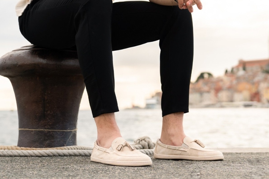 Man in cream men's everyday barefoot shoes sitting on a pier by the sea