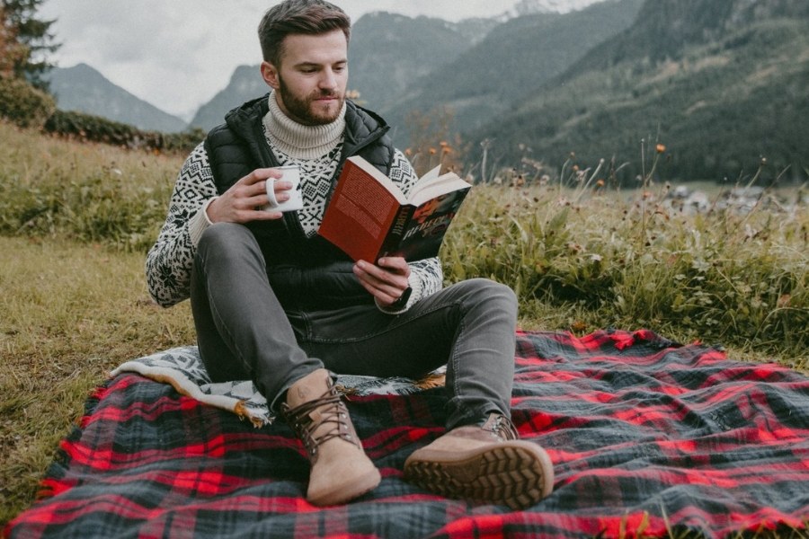 Man in brown men's autumn barefoot shoes sitting on a blanket in a mountain landscape Man in brown men's autumn barefoot shoes sitting on a blanket in a mountain landscape