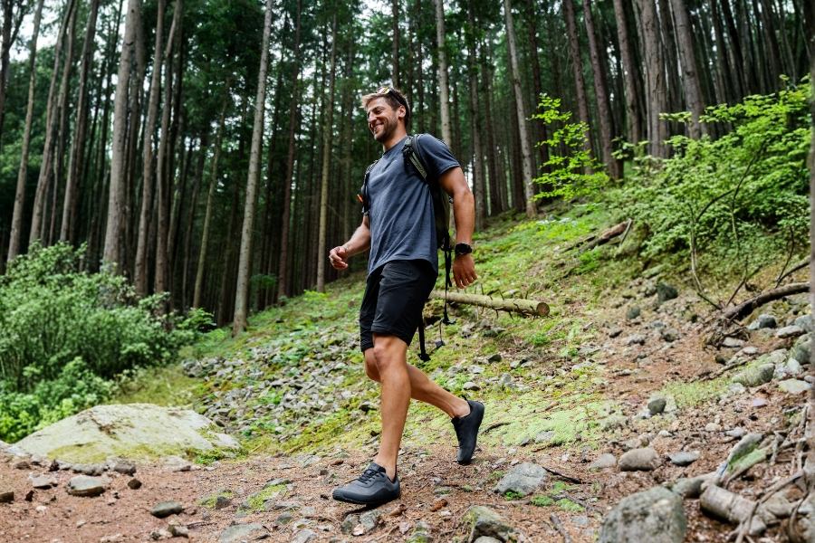 Man in grey men's outdoor barefoot shoes walking on a forest trail Man in grey men's outdoor barefoot shoes walking on a forest trail
